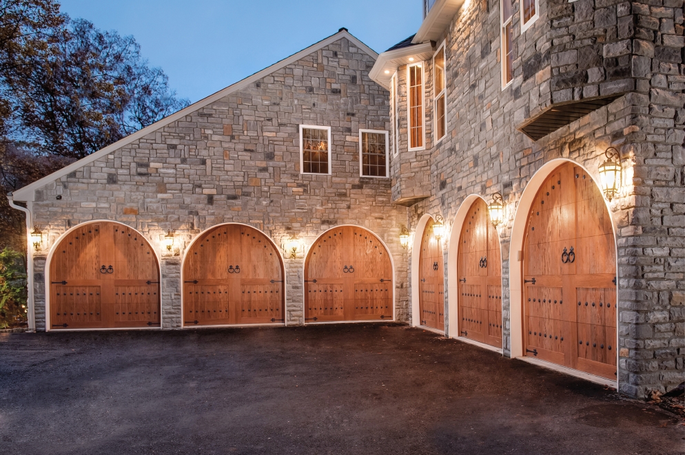 Arched Canyon Ridge Collection Garage Doors with Unique Hardware on Stone Home