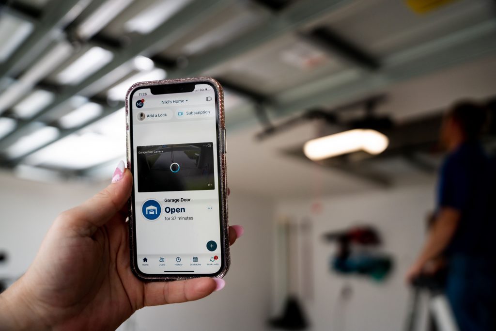 Cell phone with myQ app open and garage door opener technician in the background