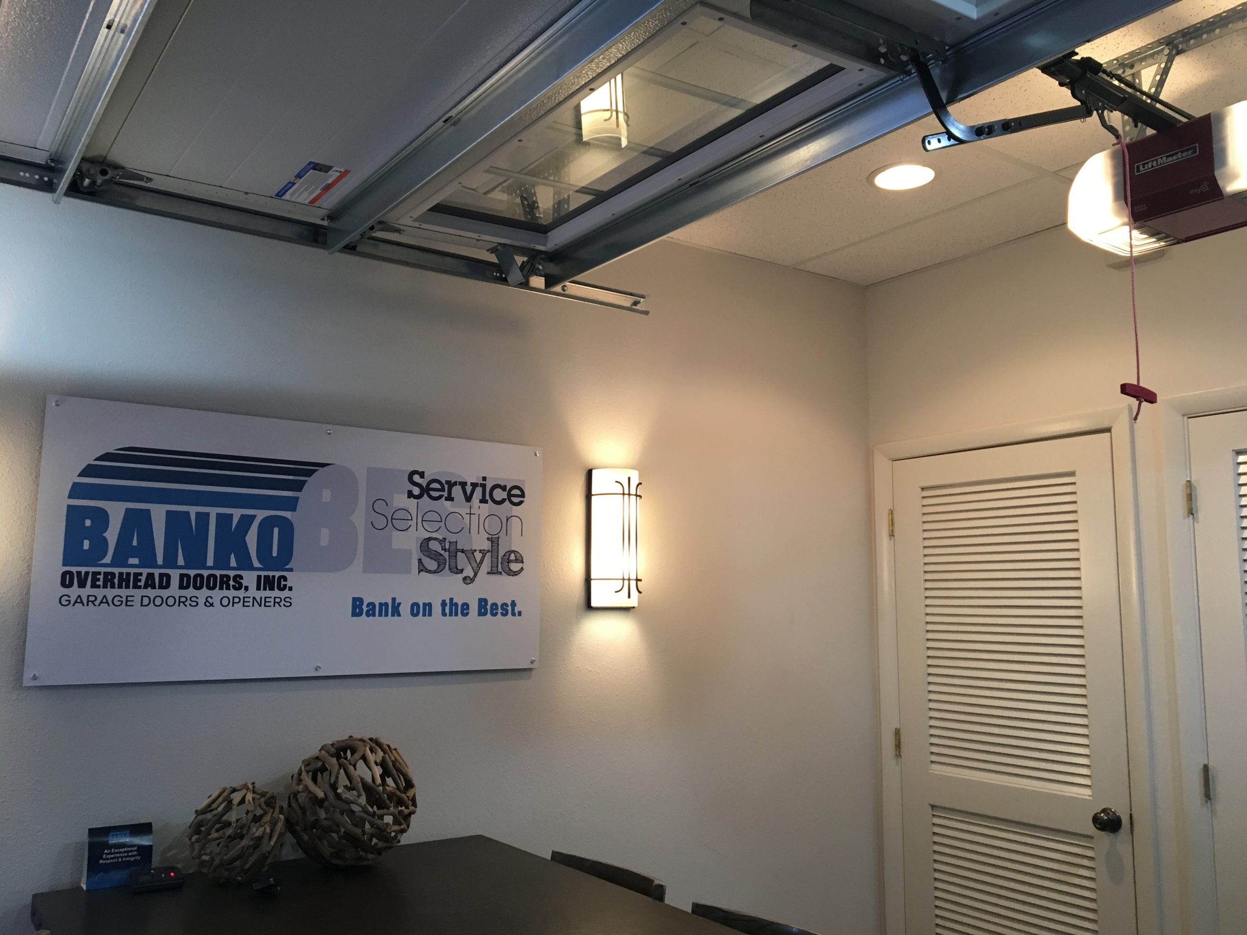 White garage door, Liftmaster garage door opener and Banko Overhead Doors, Inc. signage in the interior of our Tampa showroom